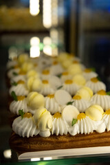 eclairs with whipped cream, covered with white protein cream, garnished with yellow marmalade and small macaroons. sweet cakes on a showcase in a cafe. confectionery concept, free space