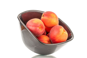 Several ripe red apricots on a black ceramic plate, close-up, isolated on a white background.