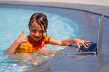 Beautiful young business girl gesturing thumb up, using laptop and working online remotely in the swimming pool.