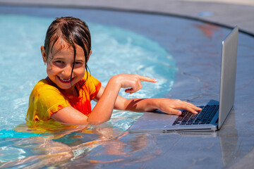 Portrait of beautiful girl using laptop in the swimming pool. She working online remotely. Summer vacations, rest and work at the same time. Horizontal image.