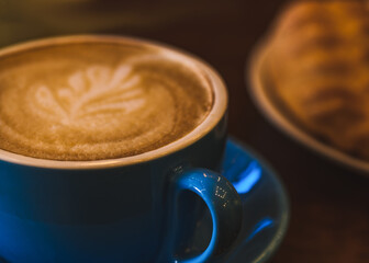 A blue cappuccino mug with a petal pattern on the foam. Minimalistic coffee mug concept.