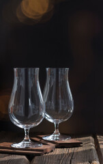 Two beautiful tall stemmed glasses on a dark pub background.