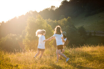 three happy young girls dance together holding hands