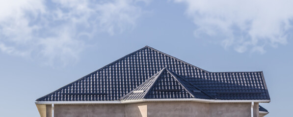 The roof of the house from a metal profile against the sky