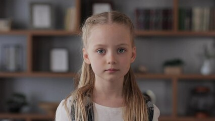 Portrait of cute little girl looking at camera. Smiling child indoors at home interior. Concept of a happy childhood.