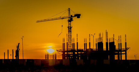Silhouette of a building under construction against the backdrop of sunset