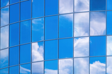 Blue glass facade of an office building. Reflection of clouds