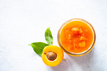 Apricot jam in glass jar, homemade preservation at white. Top view with copy space.