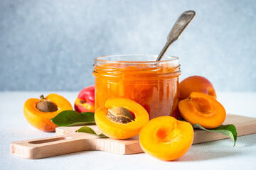 Apricot jam in glass jar, homemade preservation at white kitchen table. - obrazy, fototapety, plakaty