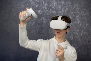 Young teenage student wearing virtual reality glasses on gray background