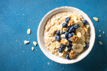 Oatmeal porrige with berries and nuts at blue background. Top view.