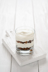 Dessert with mascarpone cheese and granola on a white wooden background.