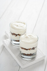 Dessert with mascarpone cheese and granola on a white wooden background.