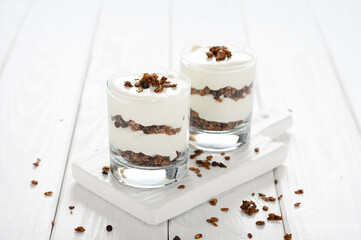 Dessert with mascarpone cheese and granola on a white wooden background.