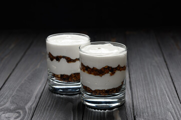 Layered dessert with granola on a wooden dark wooden background.