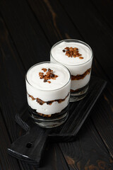 Greek yogurt with granola on a wooden dark wooden background.