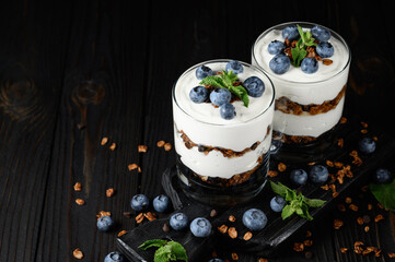 Dessert with mascarpone cheese, fresh blueberries and muesli in a glass on a rustic background.