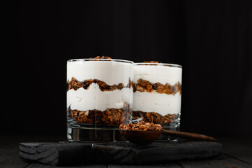 Layered dessert with granola on a wooden dark wooden background.