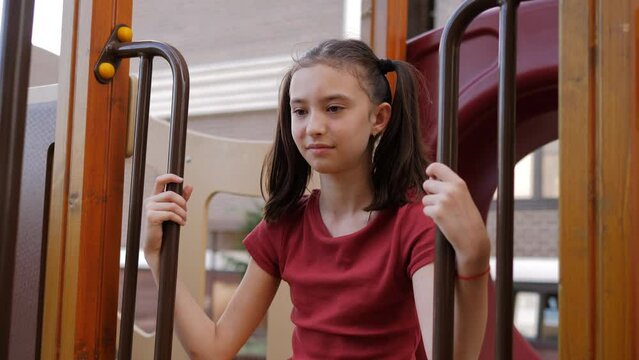 A 9-year-old girl is sitting on the playground and smiling. A carefree childhood.