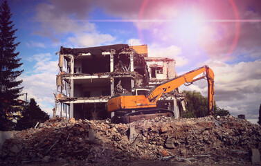 An excavator lit by sunlight during the demolition of a building. Koparka oświetlona światłem słonecznym podczas rozbiórki budynku. © jarizPJ