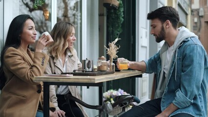 Video of group of cool friends sharing a brunch together while talking and using the smartphone on the healthy coffee shop terrace. - Powered by Adobe