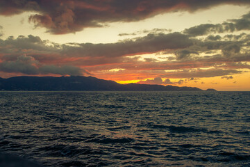 Beautiful sunset behind the mountains on the island of Crete. Golden colors in the Greek sky