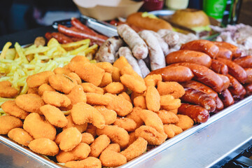 Meat, sausages, french fries in metal tray at street food festival