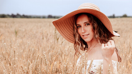 Woman field wheat. Happy young woman in sun hat in summer wheat field at sunset. Nature, summer holidays, vacation and people concept.