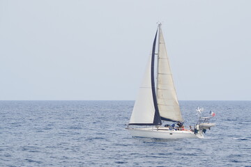 Płynący biały jacht nad morzem pod francuską flagą