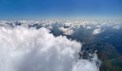 Naklejka na ściany i meble Aerial view from airplane window at high altitude of earth covered with white puffy cumulus clouds