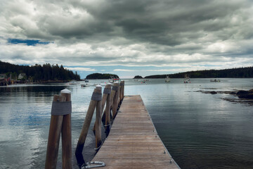 Pier in the bay among the islands overgrown with forest. Coast of Maine. USA
