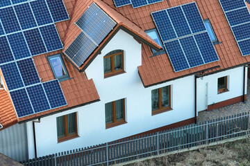 Fototapeta premium Residential house with rooftop covered with solar photovoltaic panels for producing of clean ecological electrical energy in suburban rural area. Concept of autonomous home