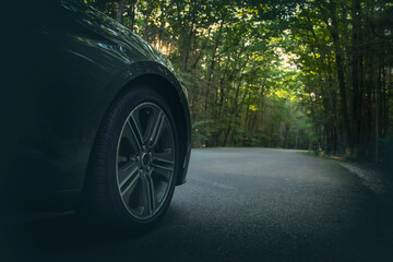 The front of a car with a wheel standing on a forest road. Driving atmosphere.