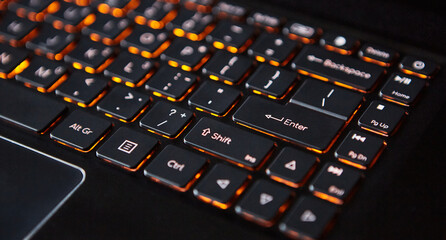 Close-up of a laptop keyboard with orange backlight.