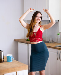 Relaxed attractive woman dancing at kitchen table at home.