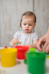 One girl small caucasian toddler child playing with colorful plasticine on the table at home alone childhood and growing up development concept copy space