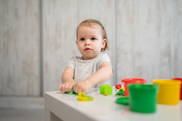 One girl small caucasian toddler child playing with colorful plasticine on the table at home alone childhood and growing up development concept copy space