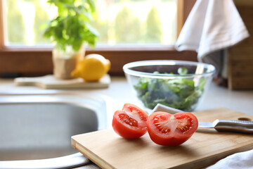 Cut fresh tomato and knife near sink in kitchen, space for text