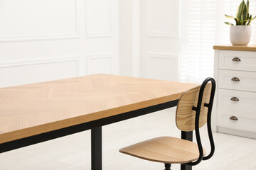 Wooden table with office chair in room