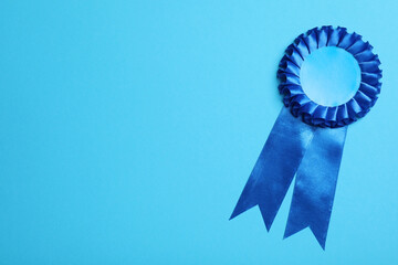 Blue award ribbon on turquoise background, top view. Space for text