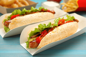 Tasty hot dogs served on light blue wooden table, closeup. Fast food