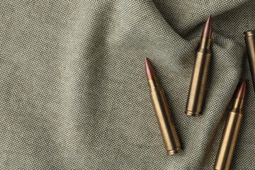 Many brass bullets on burlap, flat lay. Space for text