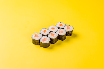 Maki roll with salmon and rice on yellow background