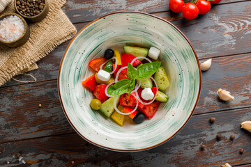 Greek salad with feta and sliced vegetables and onion top view on wooden table