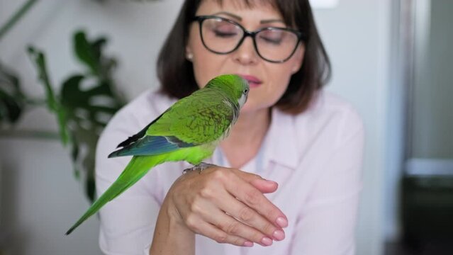 Mature woman at home with a pet parrot on her arm
