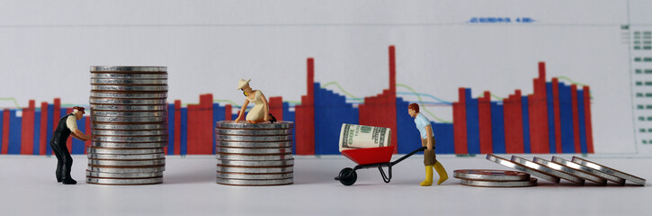 Business concept with graphs and money. A pile of coins and miniature people and graphs.
