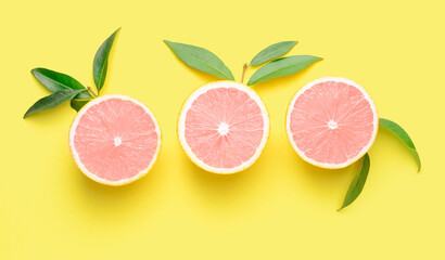 Unusual pink sliced citrus fruit on yellow background, top view