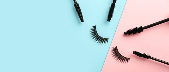 Black mascara and fake eyelashes on color background with space for text