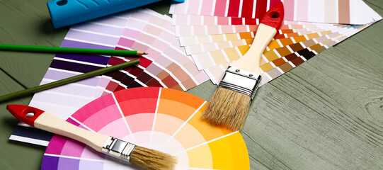 Color palettes with paint brushes on wooden background