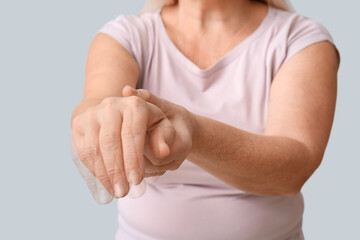 Mature woman with Parkinson syndrome on light background, closeup